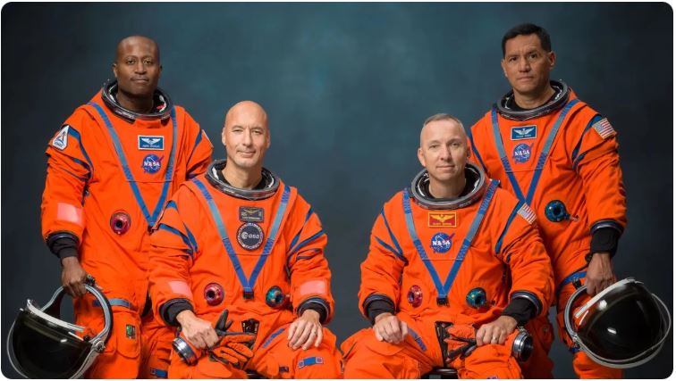 Artemis 3 astronauts Andre Douglas, Luca Parmitano, Randy Bresnik and Frank Rubio posing in orange NASA flight suits, Johnson Space Center, June 2026