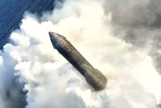 A top-down aerial drone view of SpaceX's Starship upper stage floating intact in the middle of the dark blue ocean, surrounded by a large ring of white foam and steam generated during its soft splashdown.